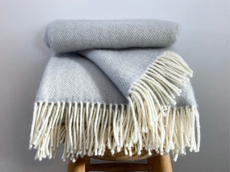 Thumbnail: Thistle Grey Richmond woollen throw on a wooden stool – crafted from 100% British worsted wool in a rich heritage shade, show