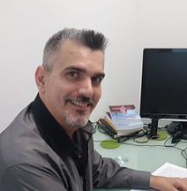 A man sitting at his desk smiles looking at the camera.