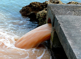 Dirty water which looks like it could be polluted running into a body of open water 