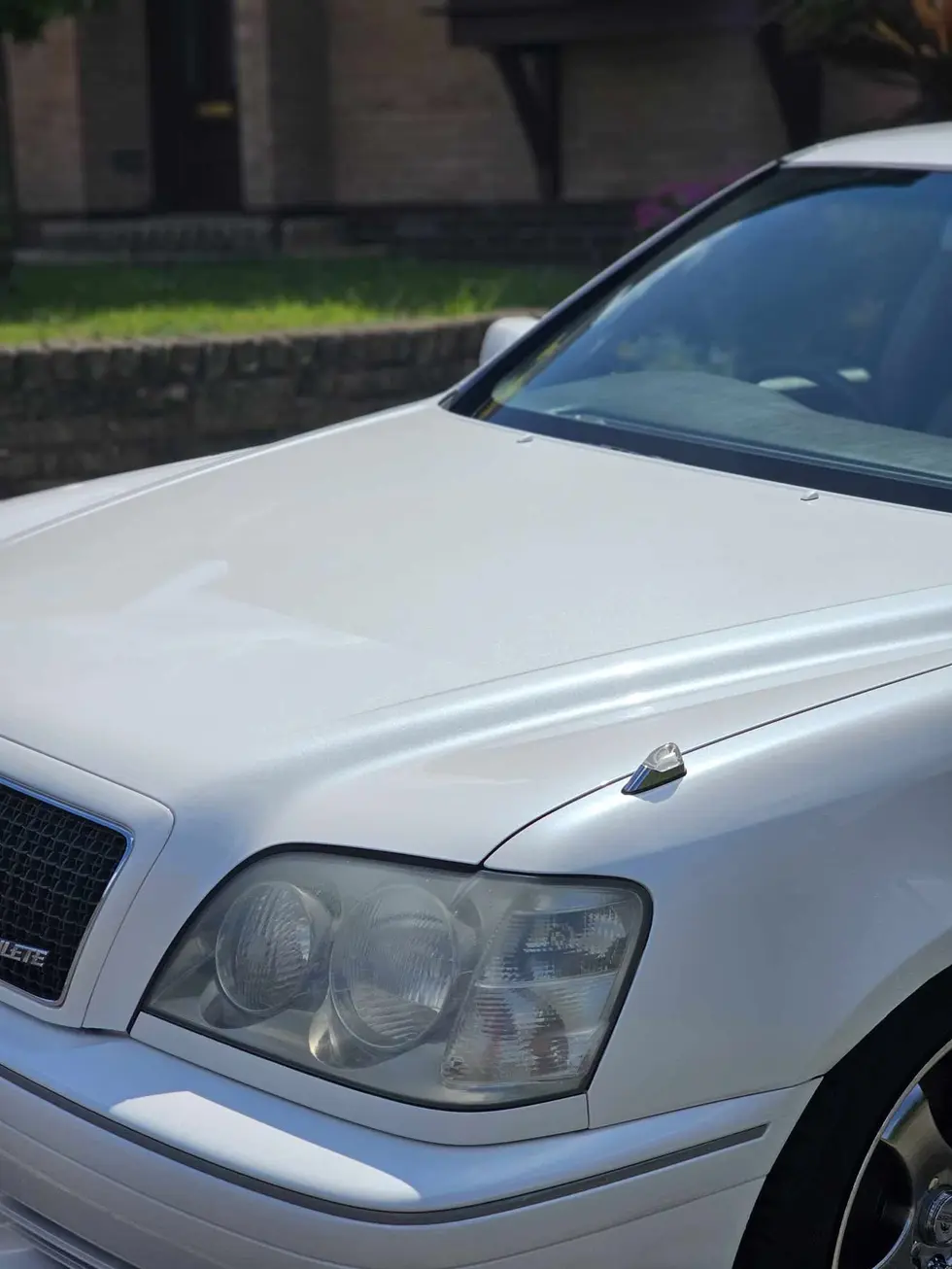the hood of a white car has a crown on it
