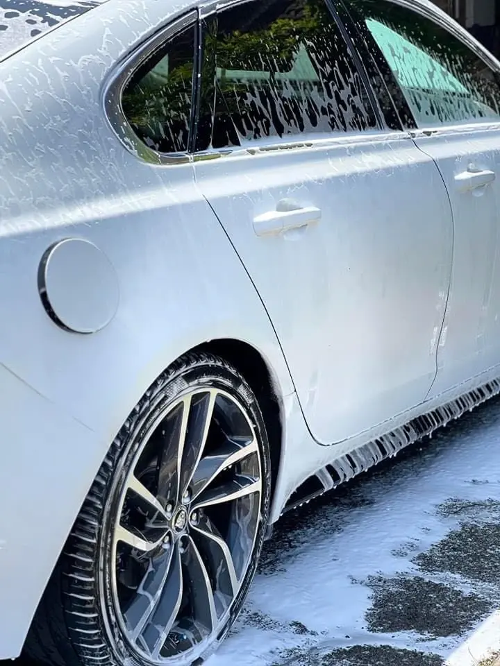 a white car is being washed with soap and water