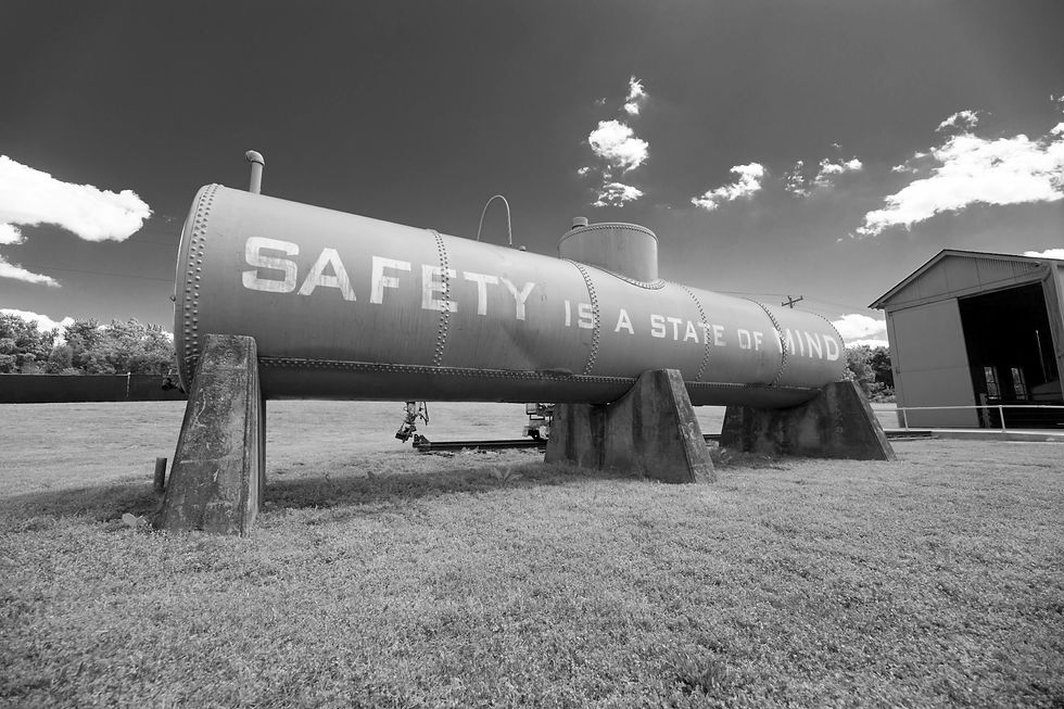 An old chemical or water tank sitting on concrete piers with a statement painted on the side that says "Safety is a state of Mind"