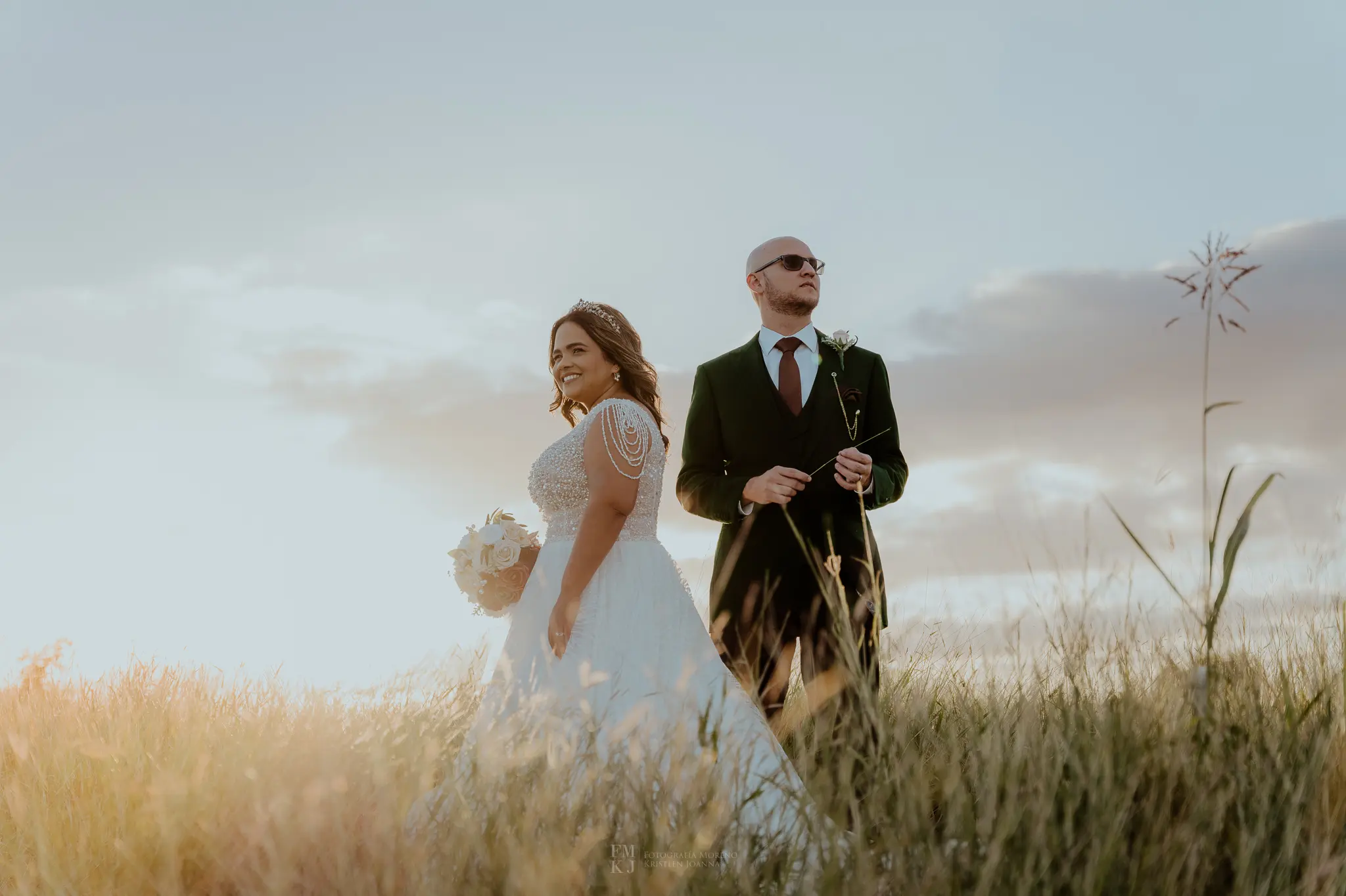 bride and groom posing in a open field at sunset
