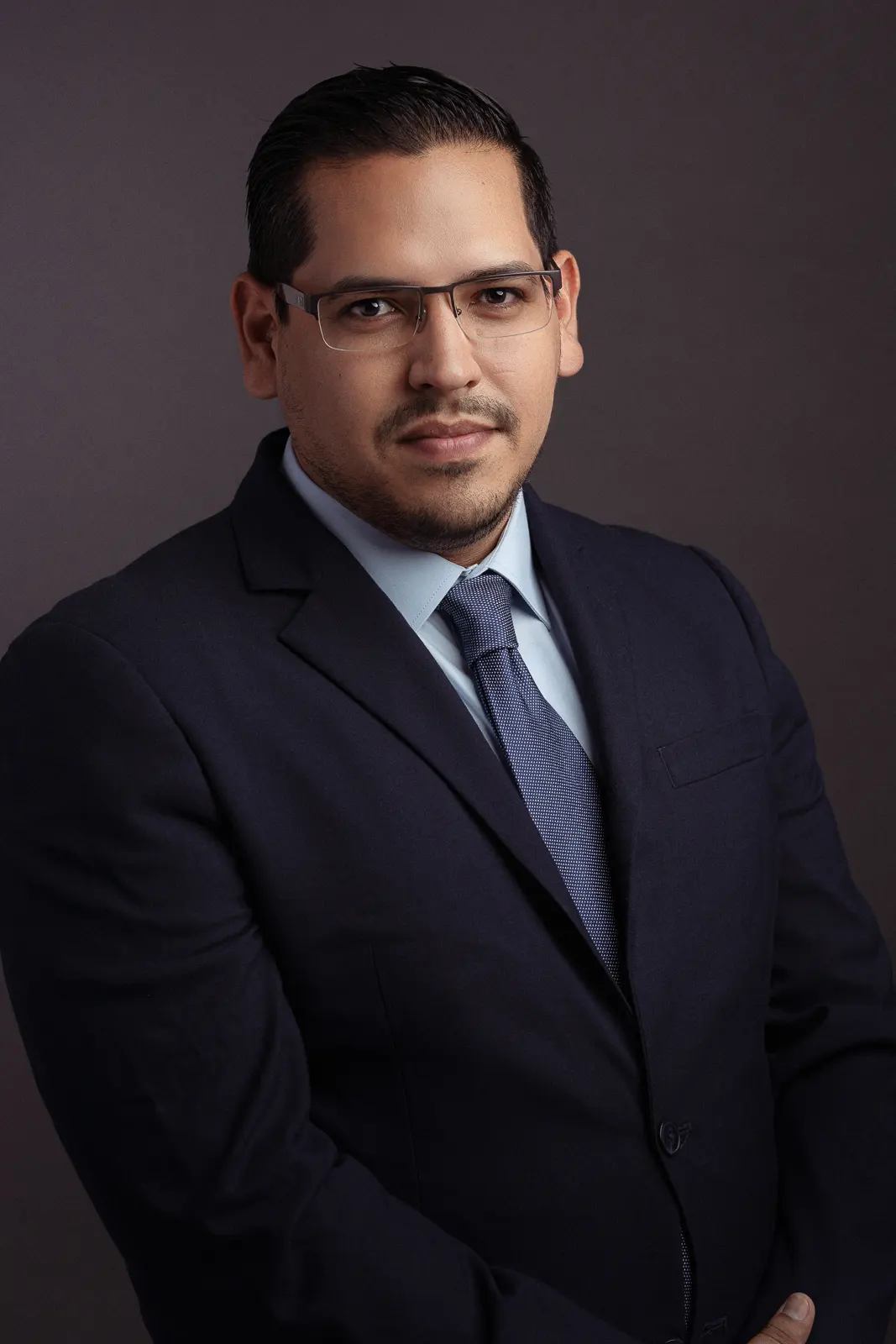 business man posing in studio photo shoot with blue tie and glasses