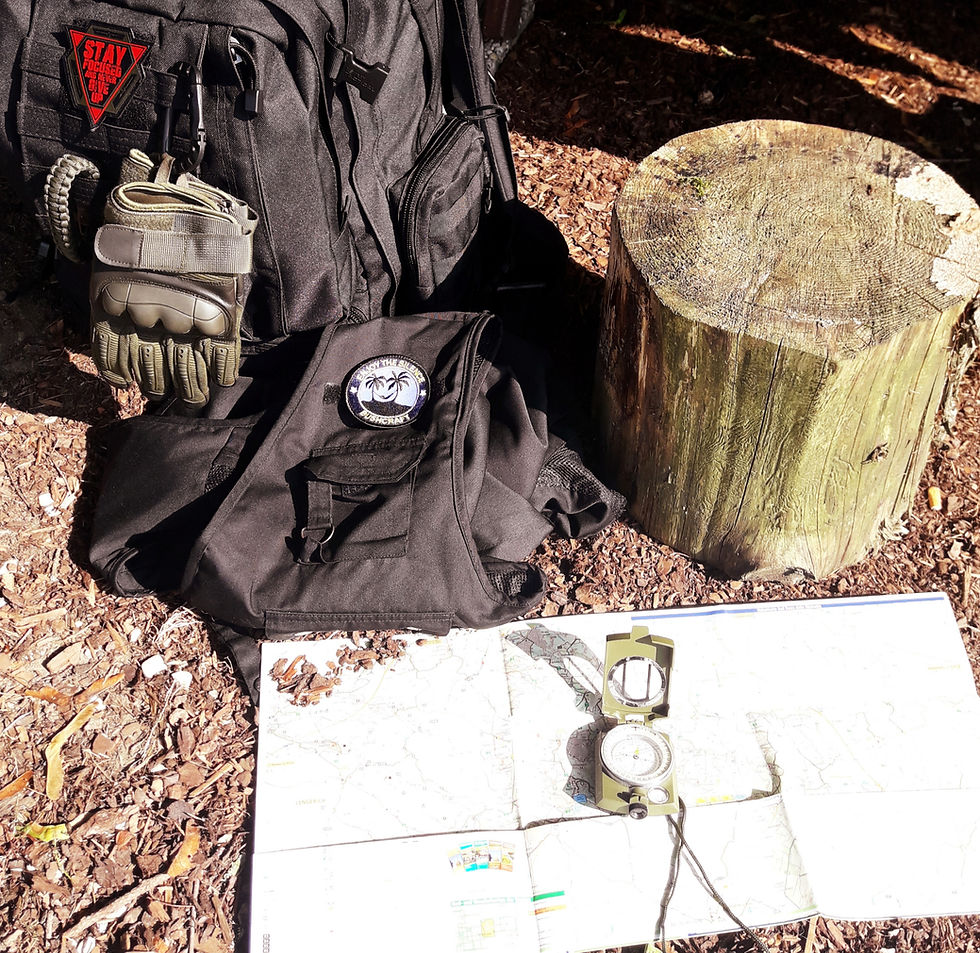 Rucksack mit Handschuhen auf Waldboden inkl. Karte und Kompass davor