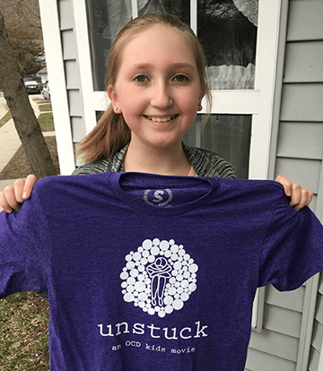Young girl holds UNSTUCK shrit