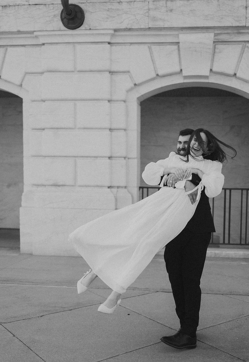 ride-to-be laughing in the wind as her fiancé lifts her outside the Detroit Institute of Arts."