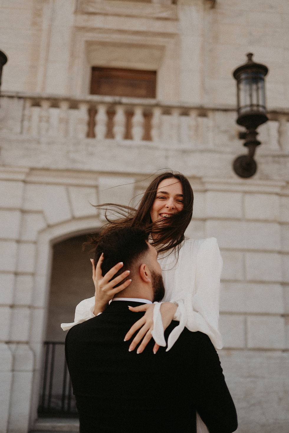 ride-to-be laughing in the wind as her fiancé lifts her outside the Detroit Institute of Arts."