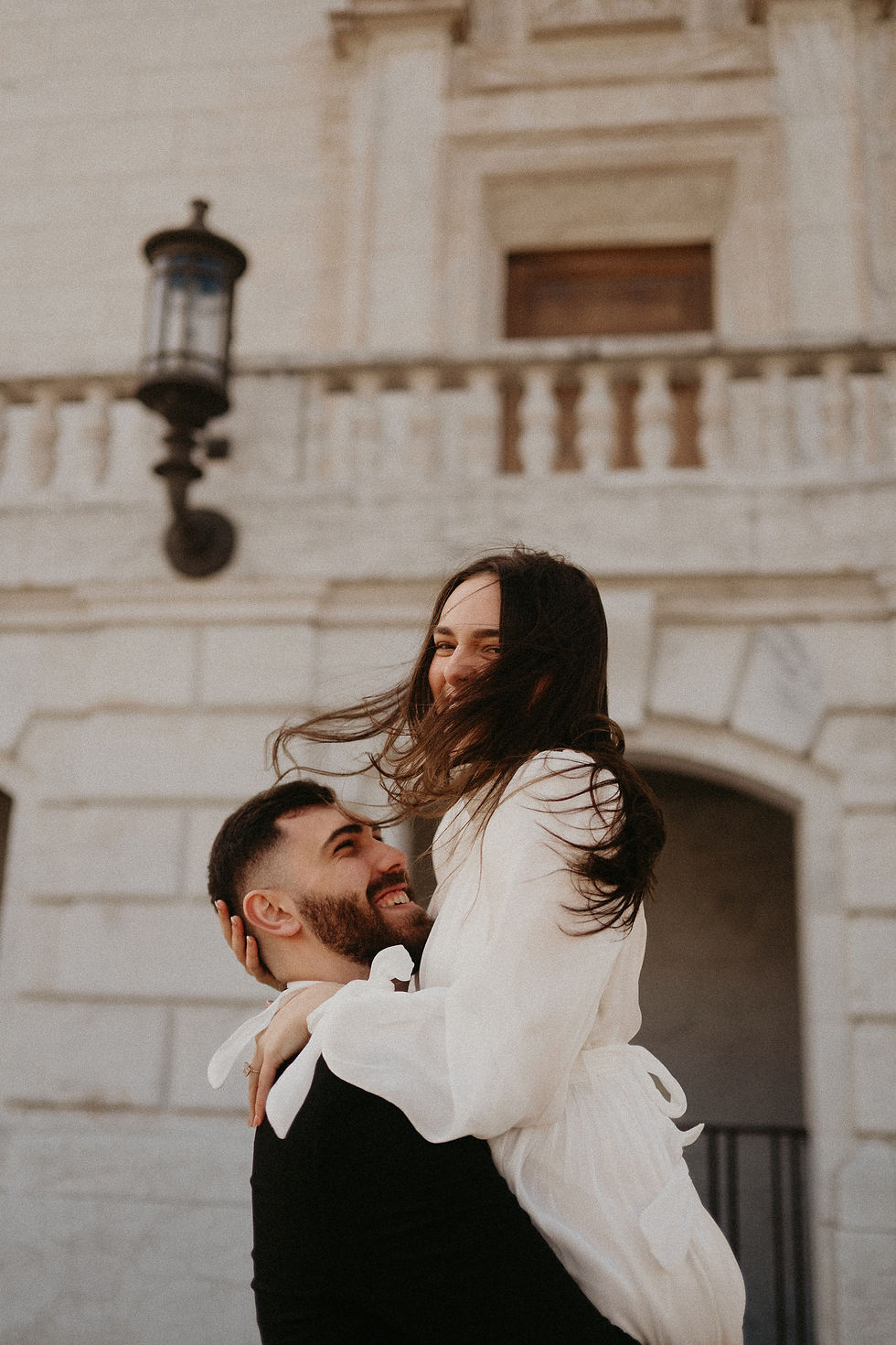 ride-to-be laughing in the wind as her fiancé lifts her outside the Detroit Institute of Arts."