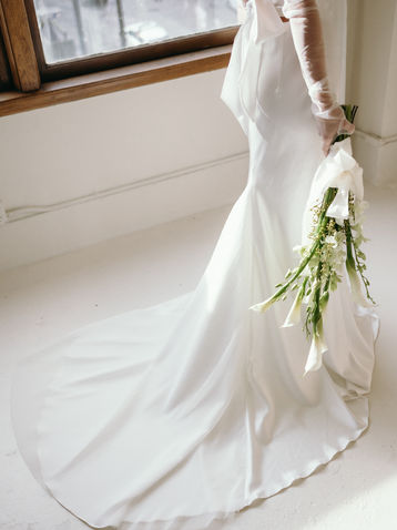 A bride in long elegant gown holding a modern and elegant bouquet made of calla lilies and orchids. Modern and sleek. Modern day bride who loves vintage.