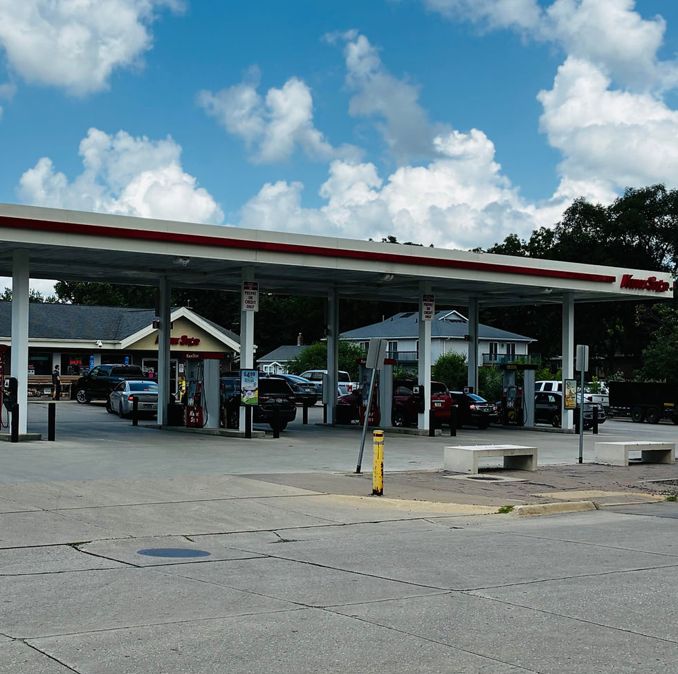 Exterior business sign in red lettering that says Kwik Star with canopy covering gas pumps