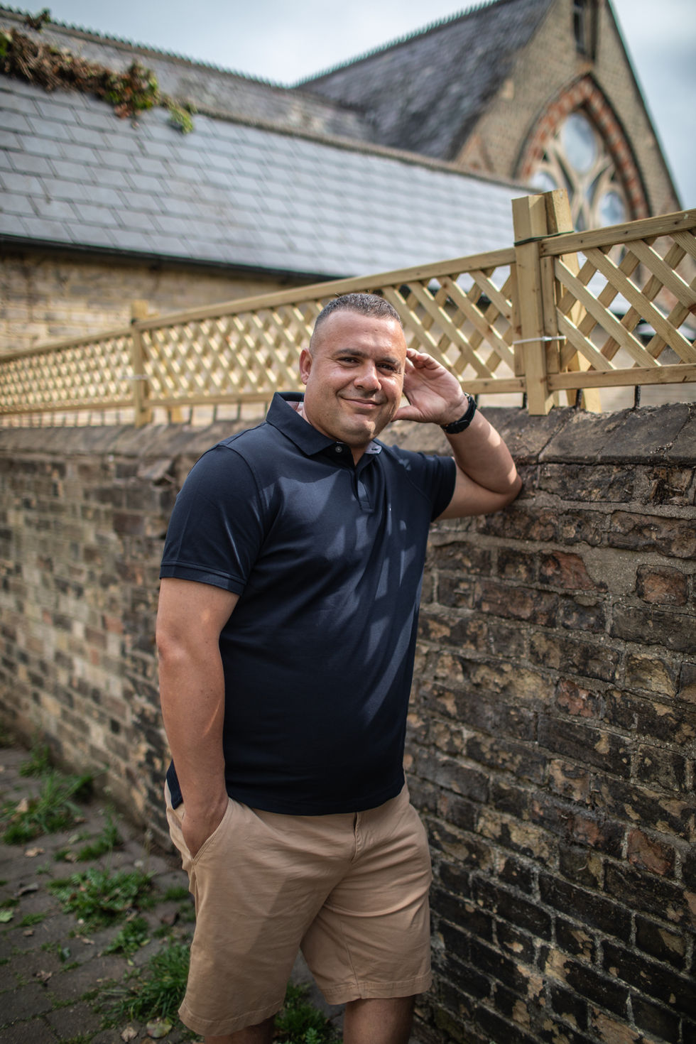 a man leaning against a brick wall with his hand on his ear