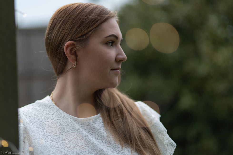 a woman in a white lace top looks to the side