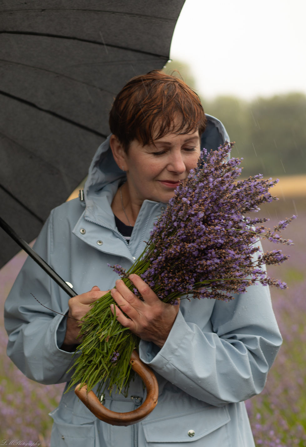 a woman holding a bouquet of purple flowers under an umbrella