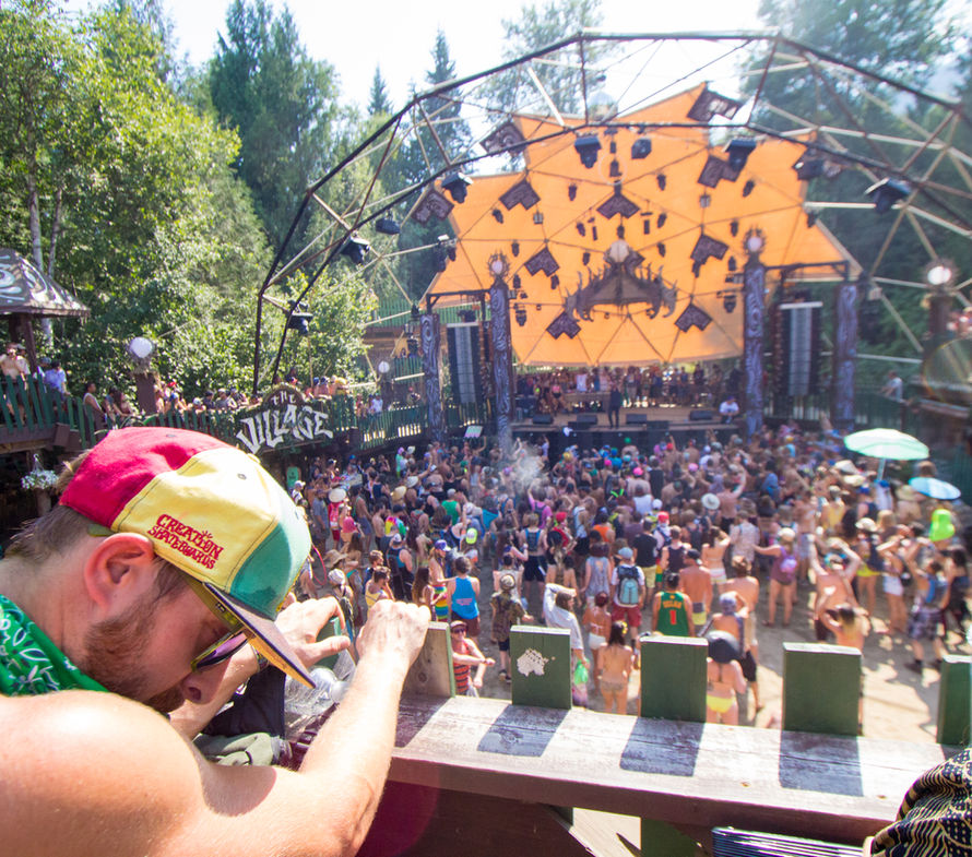 DJ leaning over the decks above the daytime crowd
