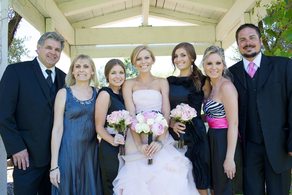 Formal group portrait of the couple with family under a wooden pavilion