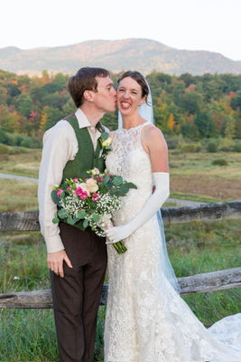 Bride holding a white and pink bouquet against the beaded bodice of her gown