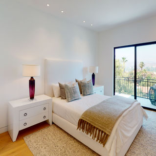 Bedroom with sliding glass doors onto a balcony above the hillside