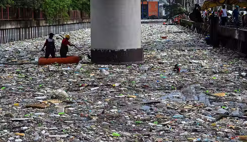 Workers collect garbage that washed into a river amid heavy southwest monsoon rains