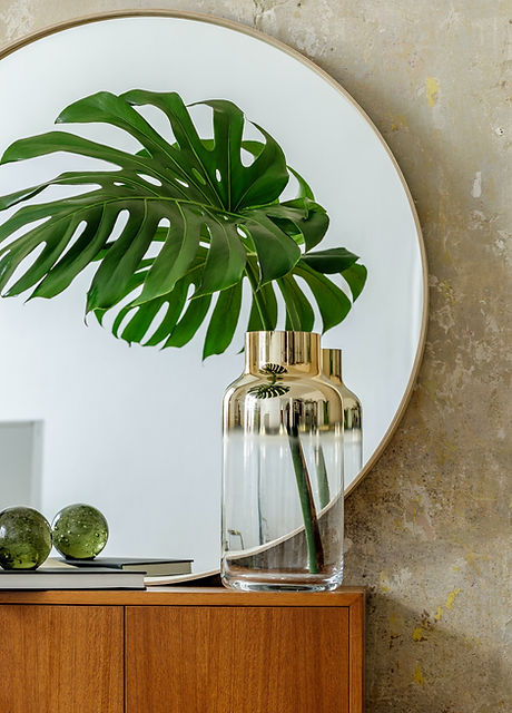 Minimalistic composition at modern retro interior with design commode, tropical leaves in vase, roun