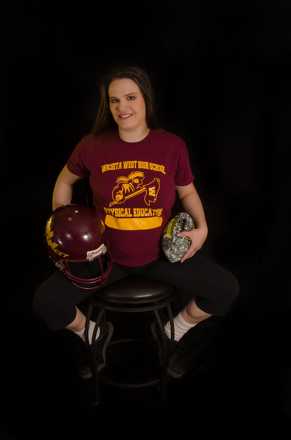 a woman holdinng a football and football helmet