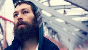 a man with a beard standing under the bridge