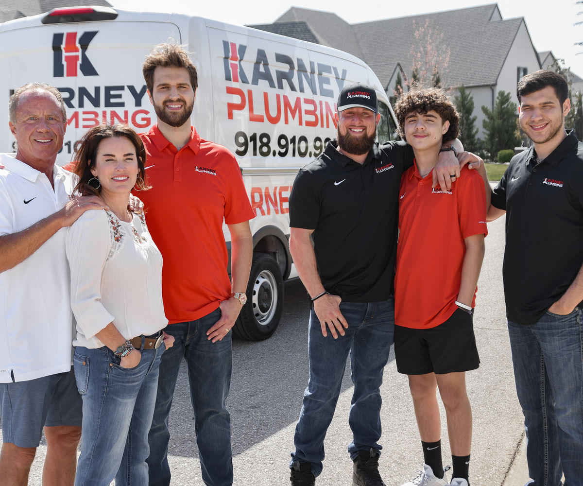 The Karney Plumbing family standing in front of their service vans