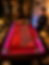 A casino dealer stands beside an illuminated roulette table in an elegant indoor venue.