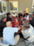 Guests seated around a red poker table with a casino dealer at an outdoor event.