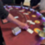 A casino dealer manages chips and cards across a purple-lit gaming table.