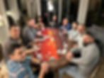 A group of guests smiles around a red poker table during a casino party.