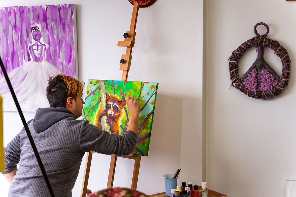 Artist painting a raccoon on canvas in a studio