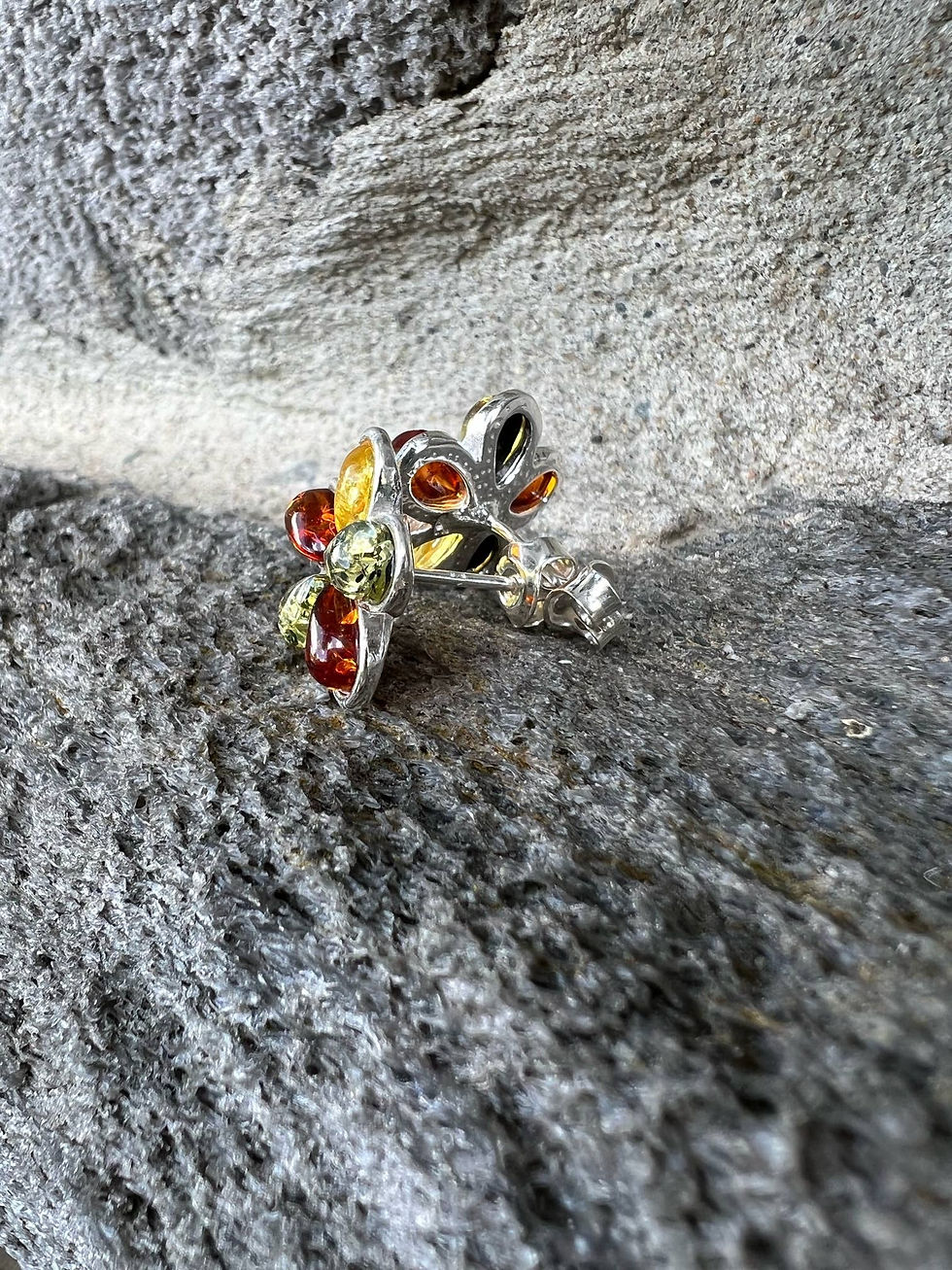 Thumbnail: Silver floral earring with colorful amber stones on a gray rock surface.