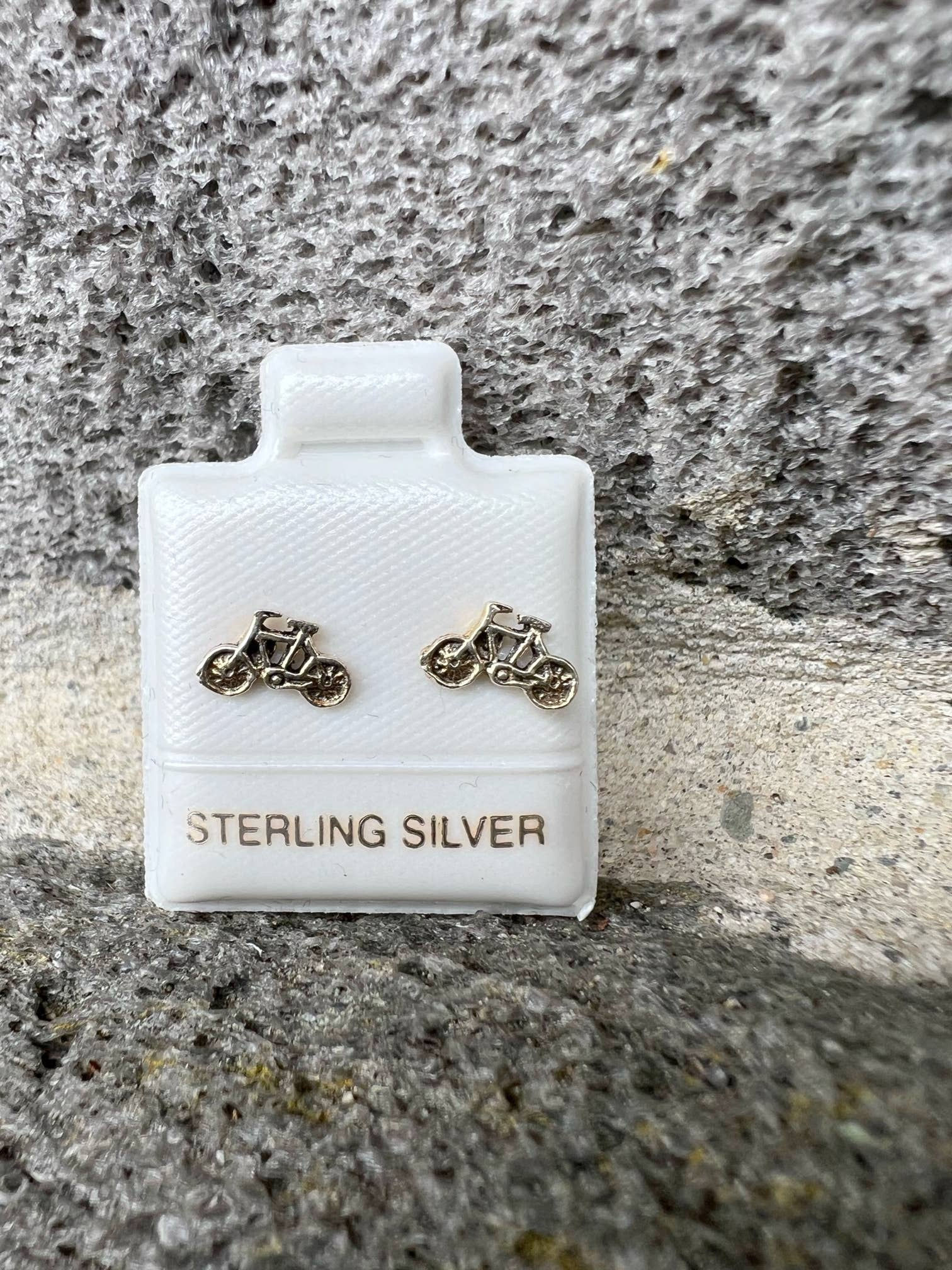 Sterling Silver motorcycle earrings on white packaging and stone background