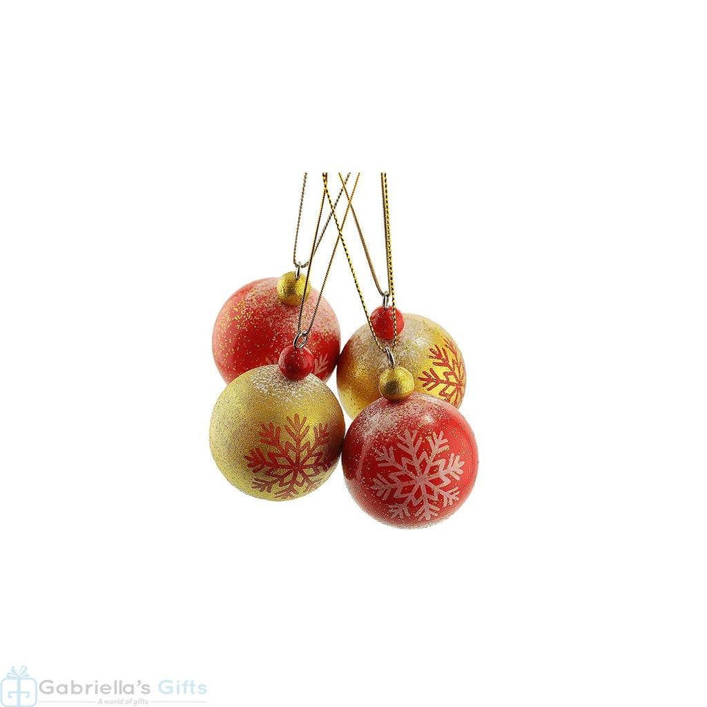 Four Christmas ornaments hanging, red and gold with snowflake designs, white background.