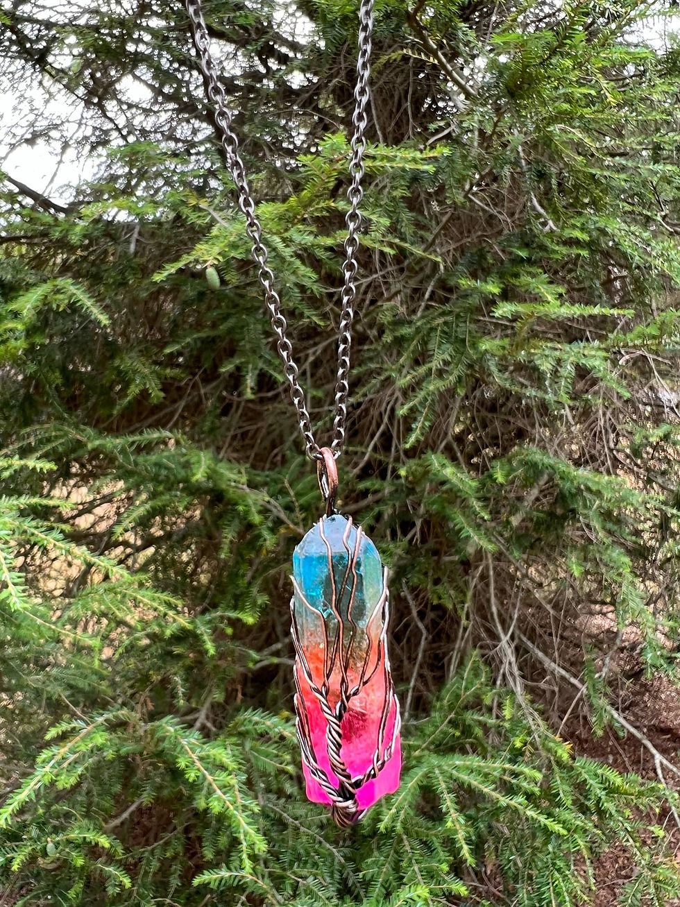 Thumbnail: A colorful crystal pendant hangs from a chain with green trees in background.
