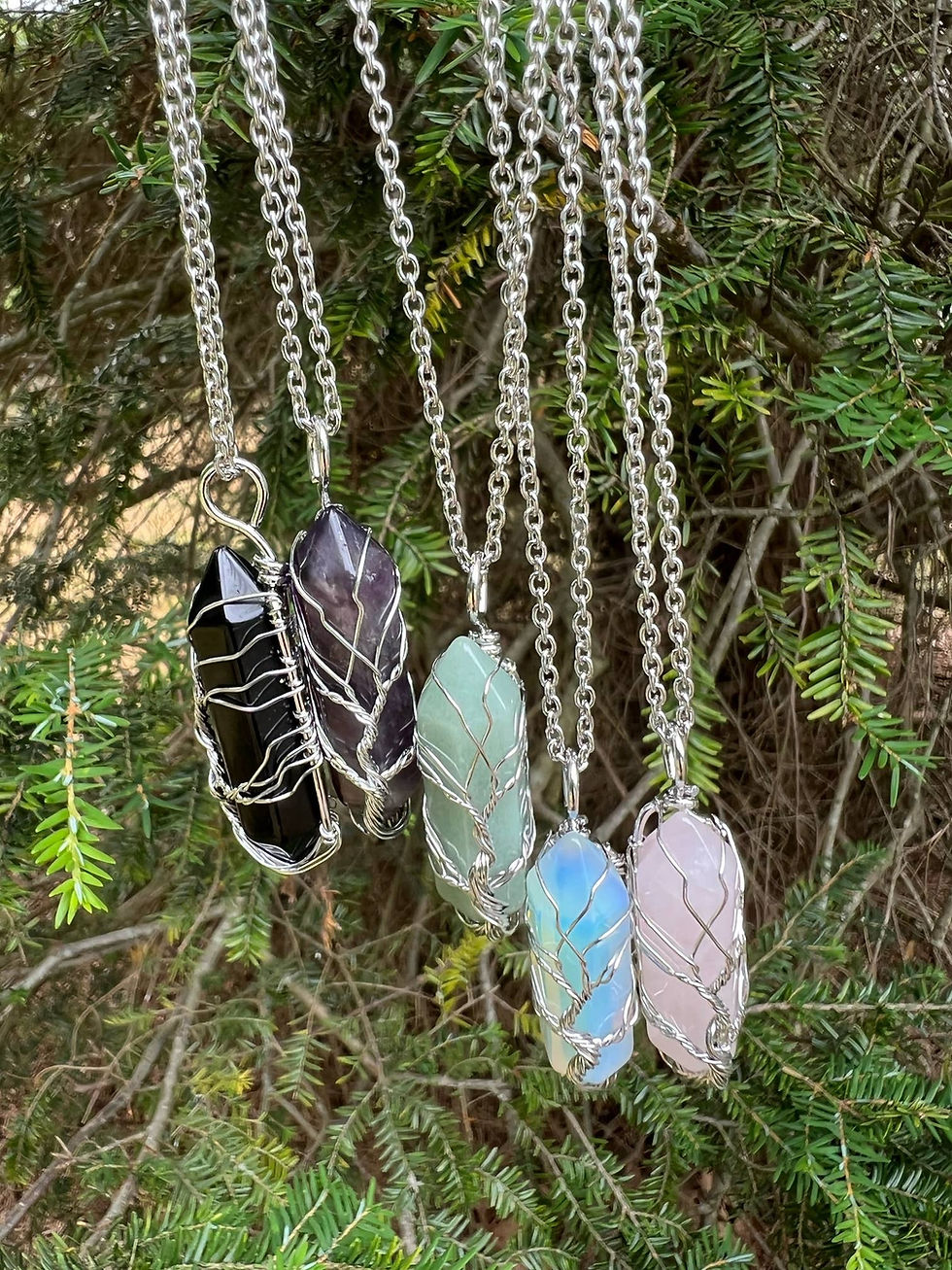 Various gemstone pendants on silver chains, displayed in front of a green backdrop.