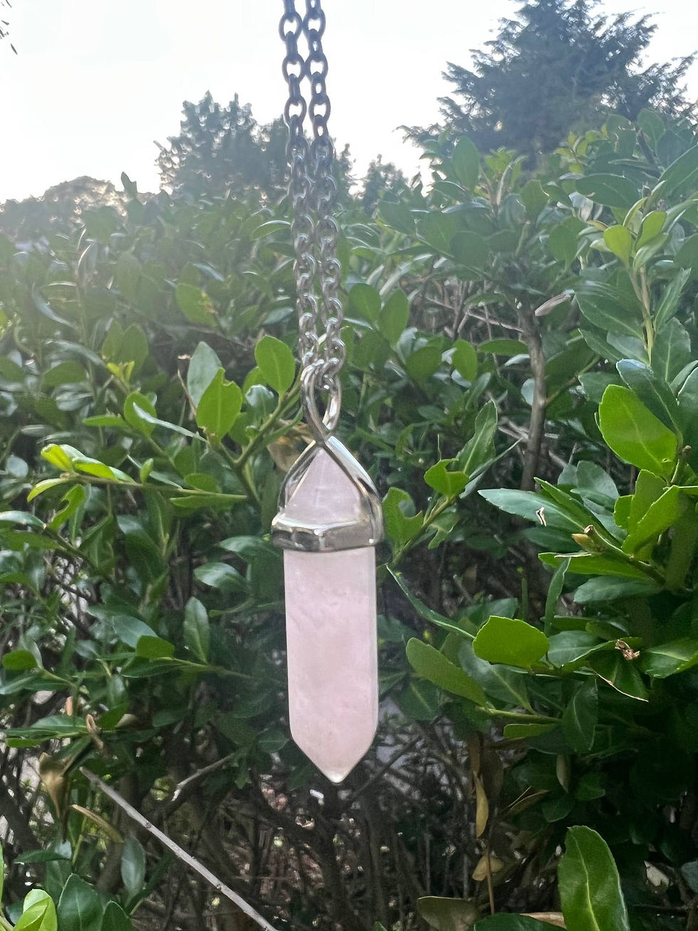 Thumbnail: Rose quartz crystal pendant on a silver chain, hanging in nature.