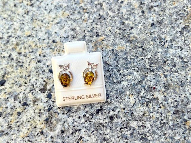 Thumbnail: Owl earrings made of sterling silver with amber gemstones on display.