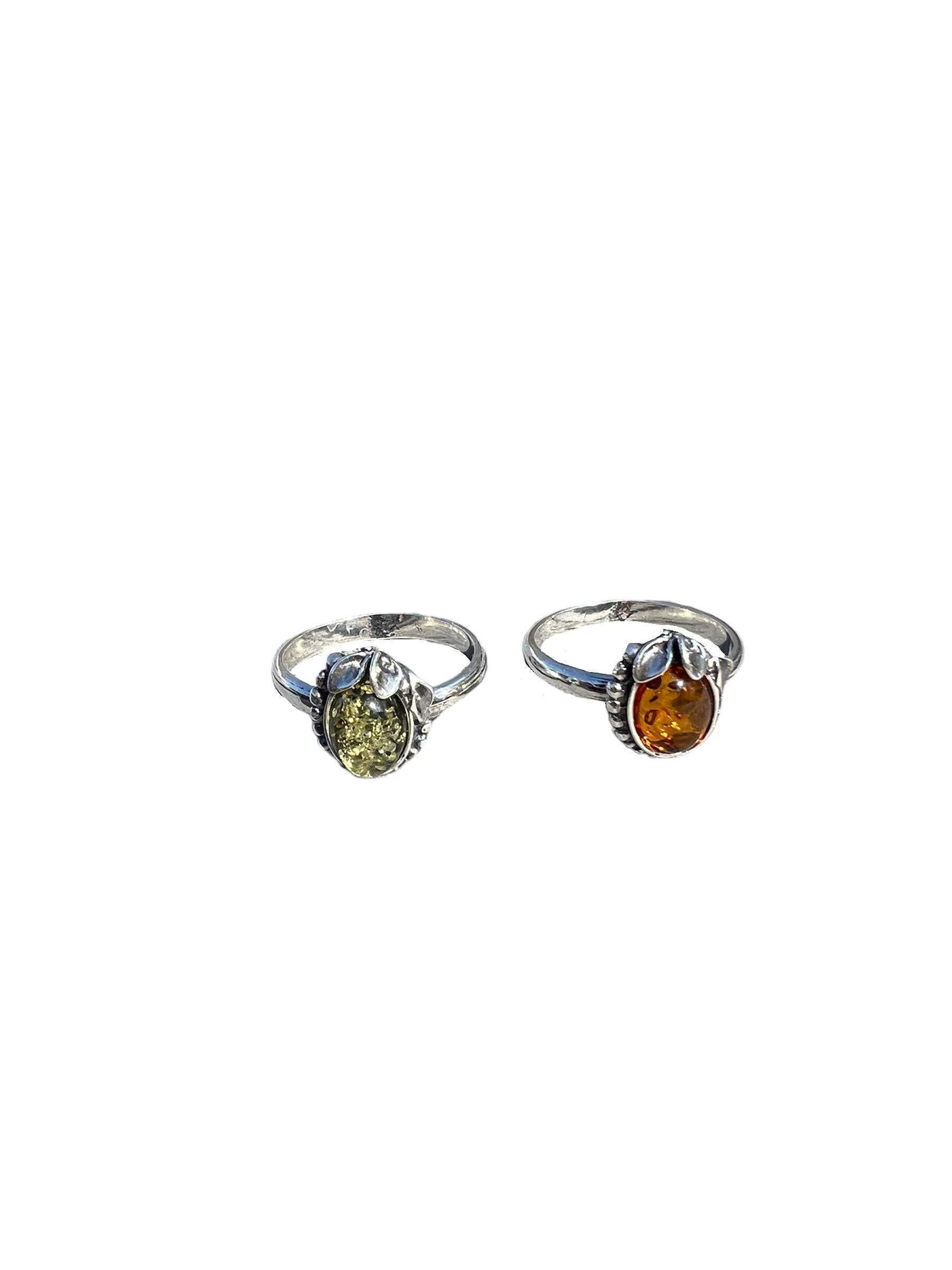 Two silver rings with green and orange gemstones, isolated on white background