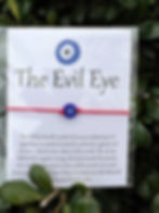 The Evil Eye bracelet on white card with text, red string, and background.
