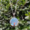 Thumbnail: Silver tree of life pendant necklace on a green leafy background.