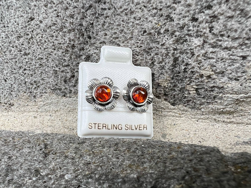 Pair of flower-shaped earrings, sterling silver, resting on a stone surface.