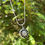 Thumbnail: Silver necklace with starburst pendant, elegant design against green foliage.