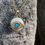 Thumbnail: Gold necklace with eye pendant on gray rock background, shining.
