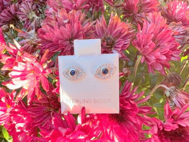 Thumbnail: Sterling Silver earrings with eye design on display against pink flowers.
