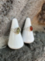 Thumbnail: Two rings displayed on white cones; one green, one orange gemstones.