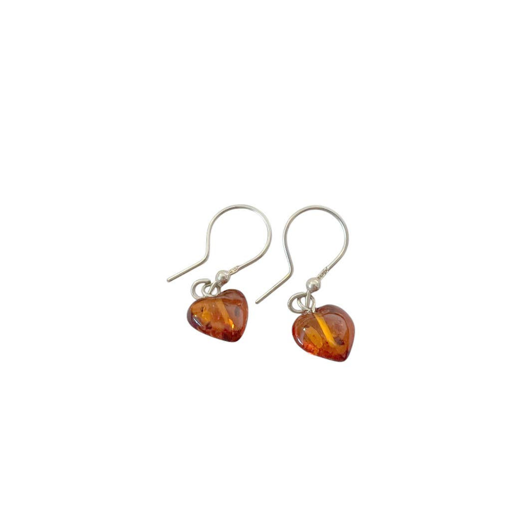 Heart-shaped amber earrings dangle, showcasing silver hooks, isolated against white background.