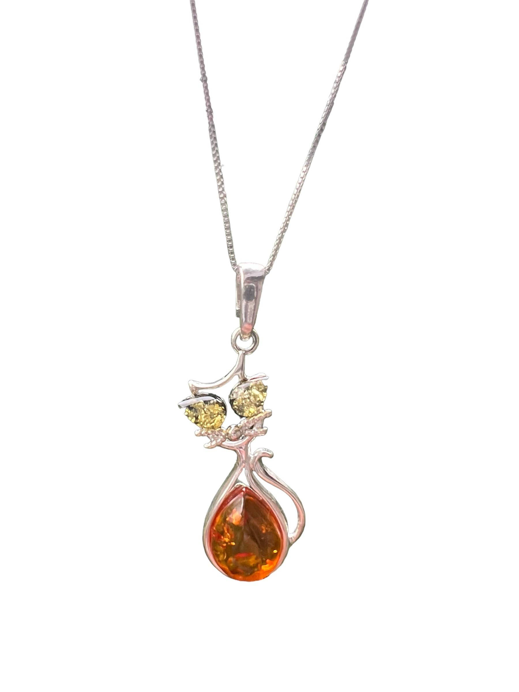 Silver necklace with a cat pendant and amber gemstone on white background.