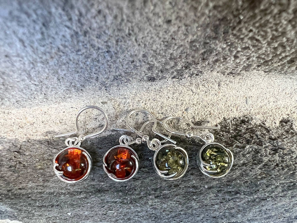 Thumbnail: Four amber earrings displayed on a textured grey surface, a jewelry close-up.